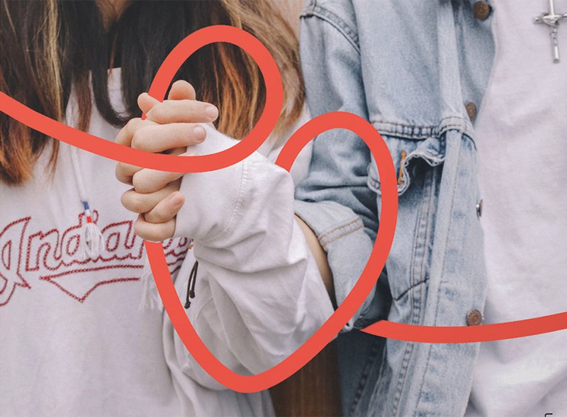 A young man and woman holding hands, with Agape's unbroken line motif forming a heart shape around their hands