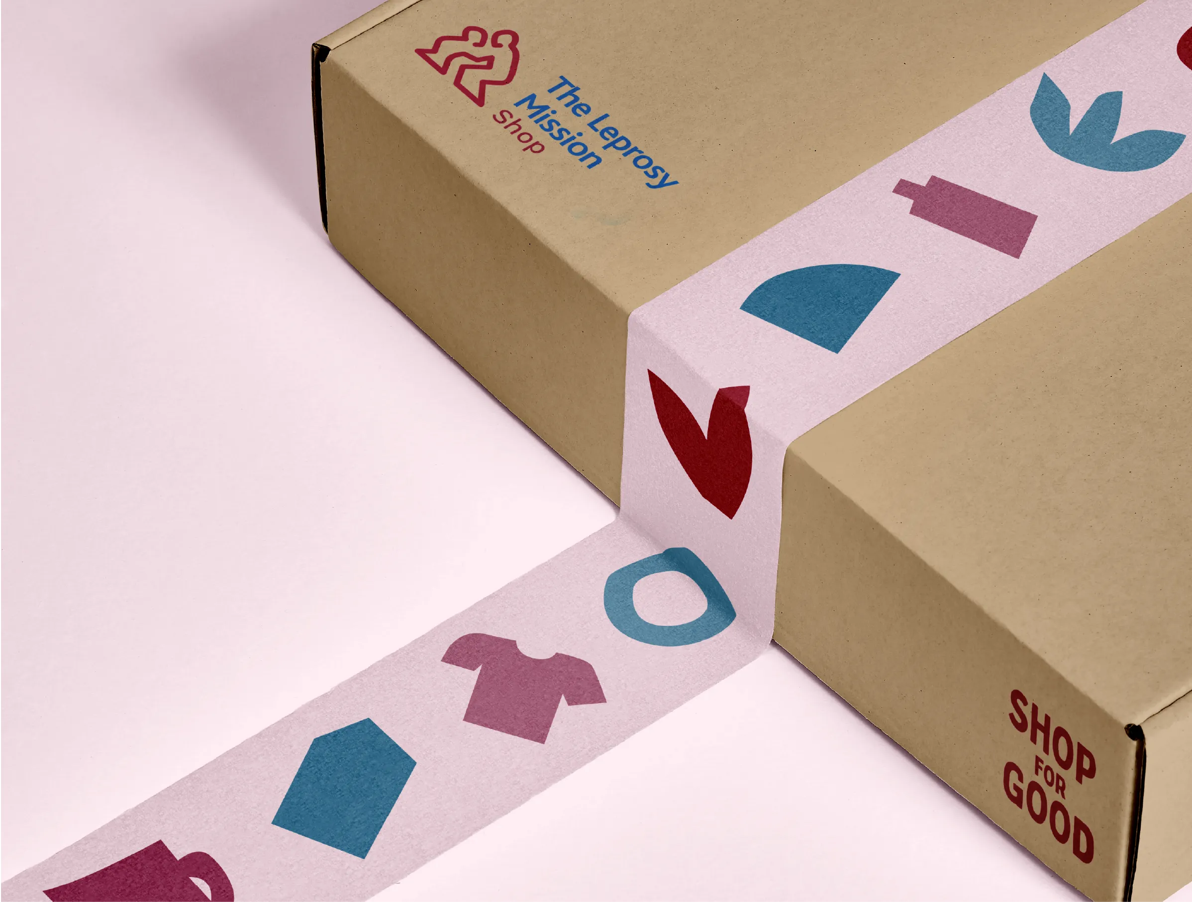 Close up of a smart brown cardboard box featuring the Leprosy Mission Shop logo, and some pink decorative parcel tape featuring some of the brand's hand cut patterns and shapes